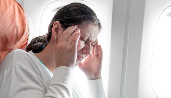 1140-woman-with-headache-on-airplane.imgcache.rev.web.700.402